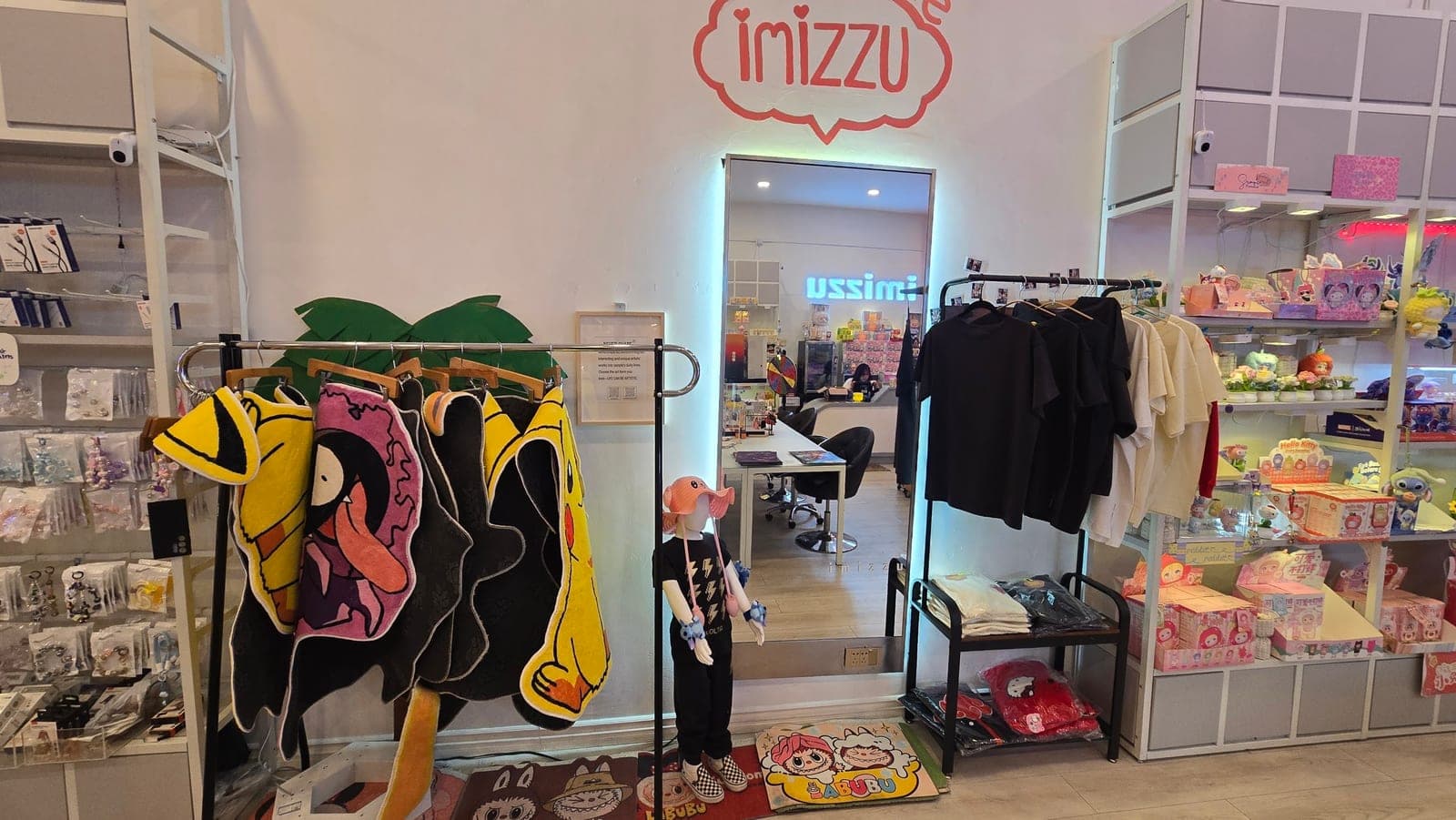 Inside imizzu: plush, shelves, a backlit mirror, and tables in the back room